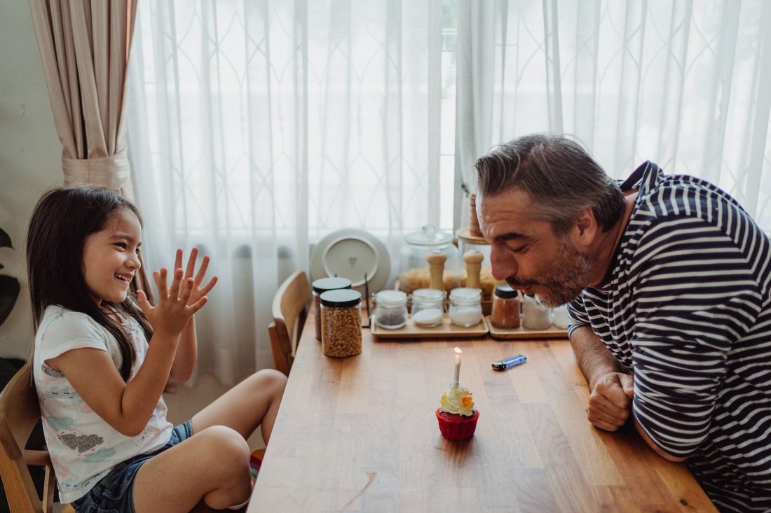Illustrative photo of a father and daughter with a cupcake candle