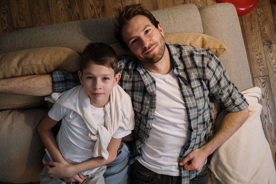 Illustrative overhead photo of a father and son relaxing on a sofa